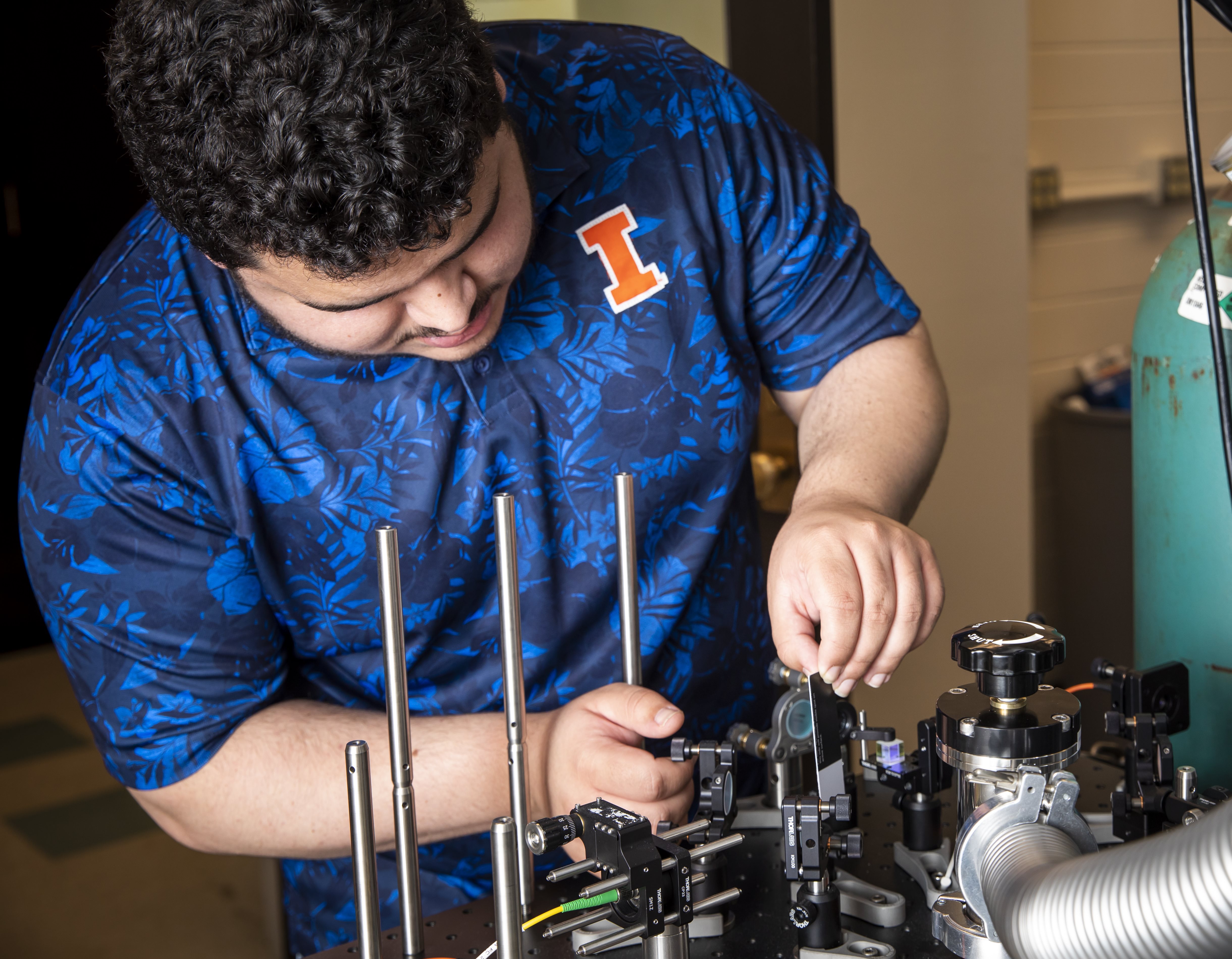 A master's student adjusts an instrument he's working on in the lab