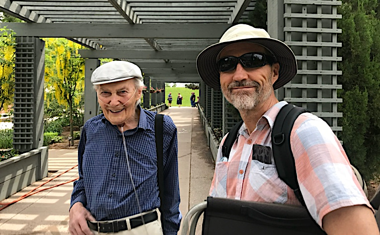 Two men standing under a pergolaAI-generated content may be incorrect.