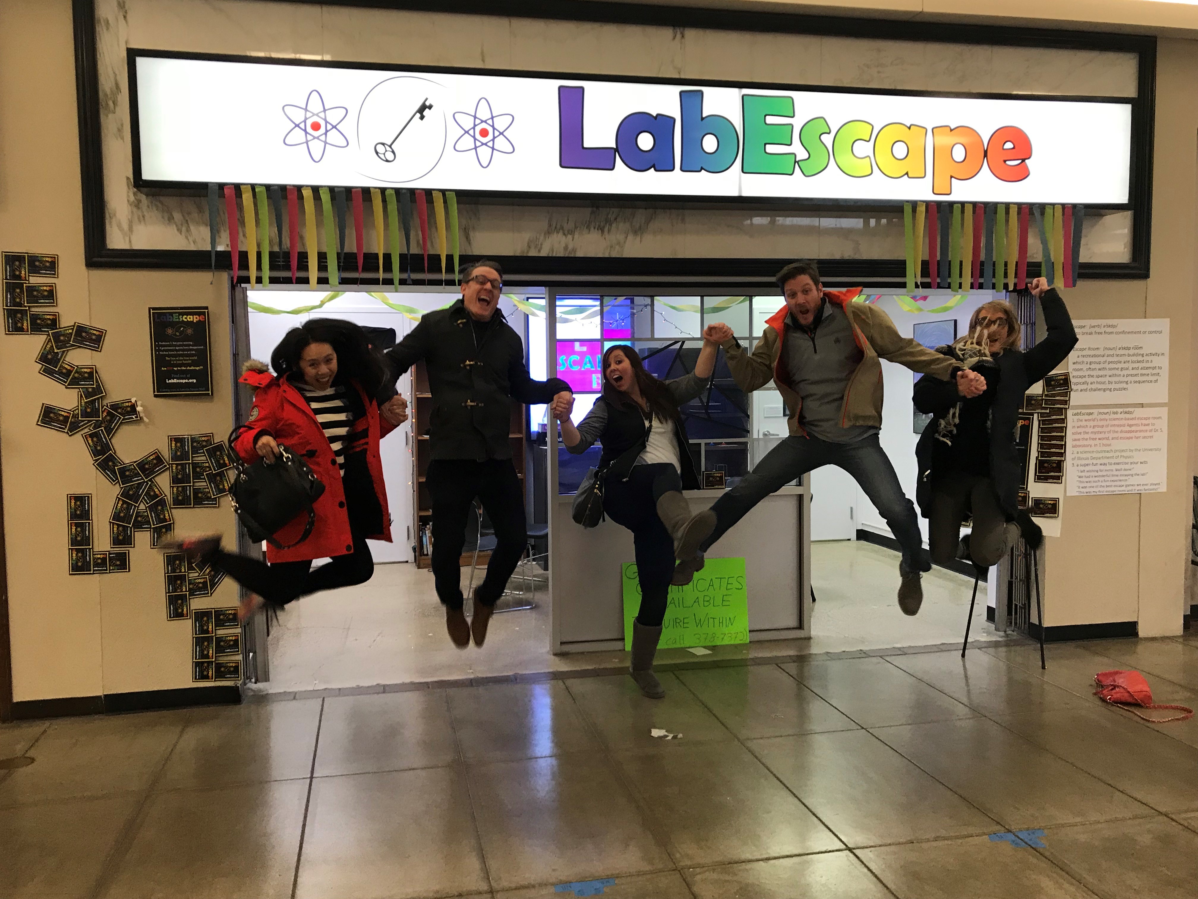 LabEscape participants jump for joy after successfully completing their mission at Lincoln Square Mall in Urbana.