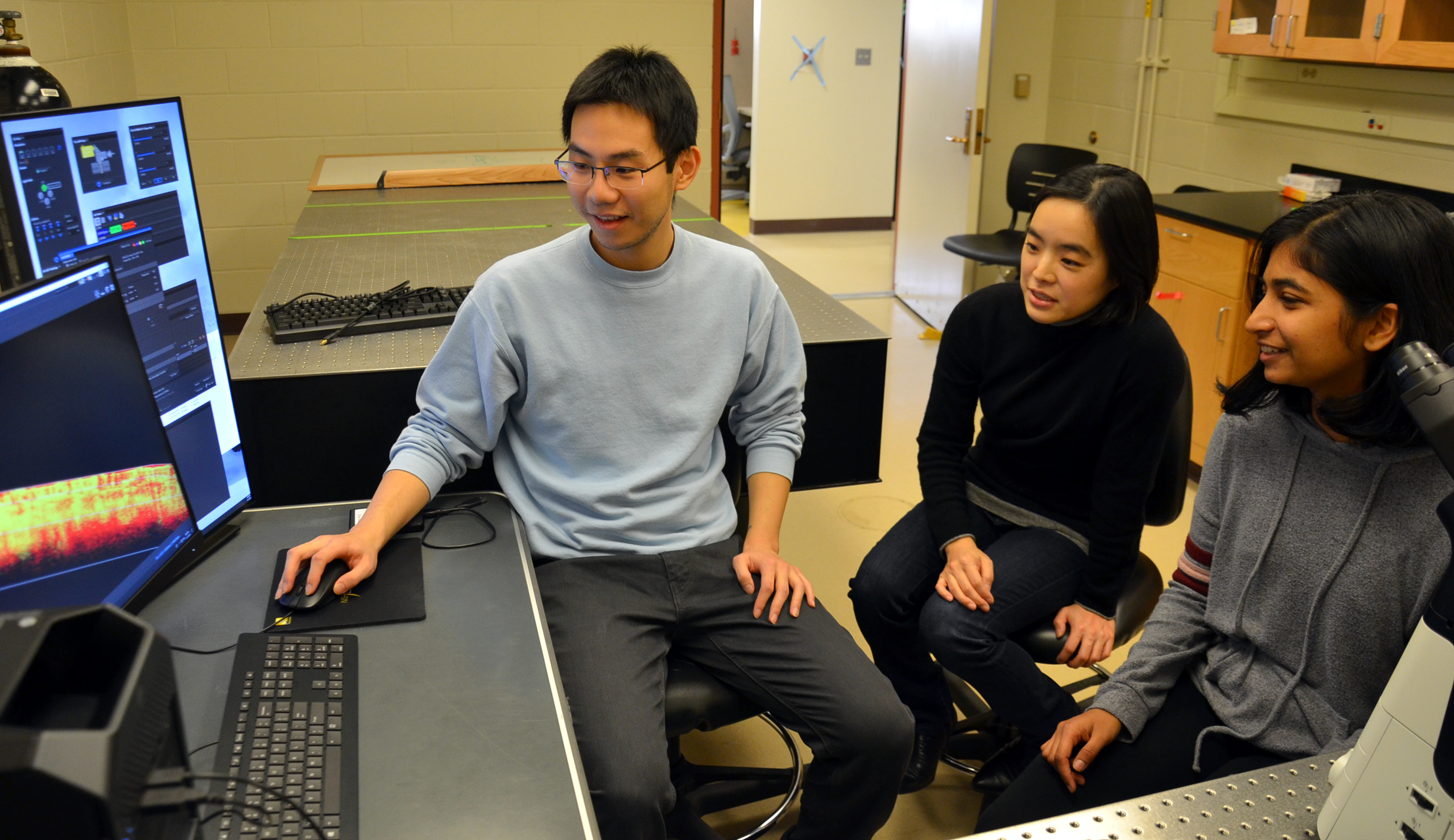 Professor Sangjin Kim (center) works with undergraduate students Zach Wang (left) and  Kavya Vaidya.