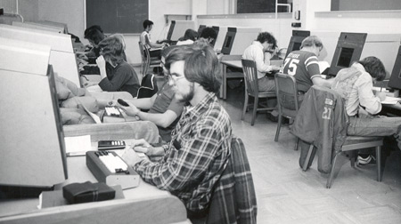 A PLATO lab in 1975; long-time Physics staff member, David D. Lesny, then a student, is seated at the first terminal.