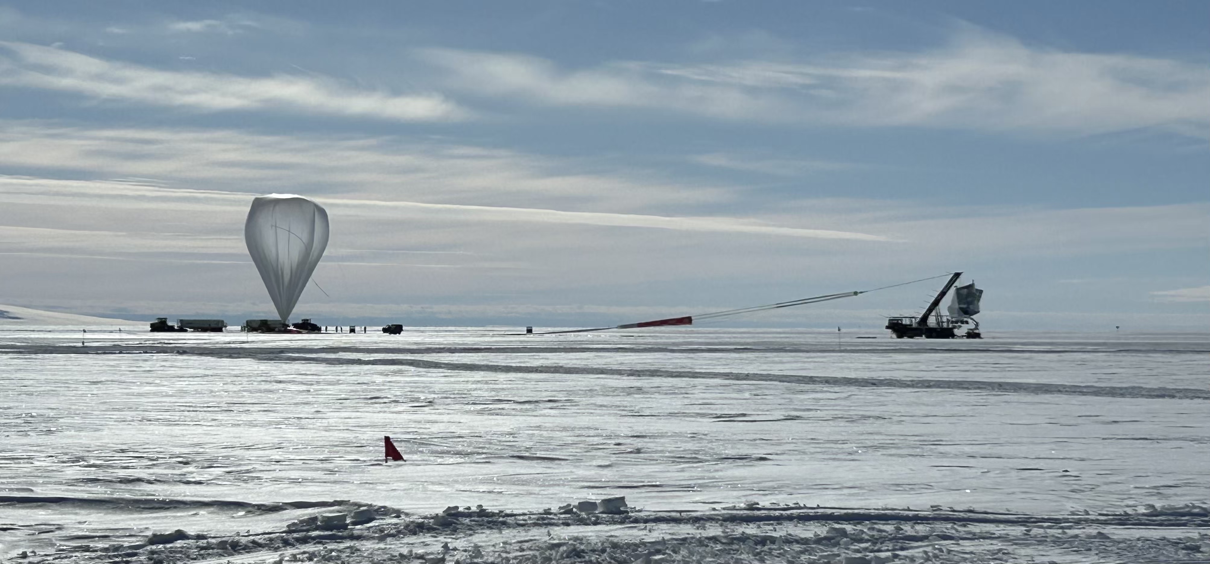 An inflated helium balloon and its payload, the SPIDER telescope, are on the launchpad at the Long Duration Balloon Facility near McMurdo Station, Antarctica. Balloon-borne instrument launches are weather-dependent and not guaranteed. The SPIDER team celebrated the instrument's successful launch on Thursday, December 22, 2022. Photo by Jeff Filippini, UIUC