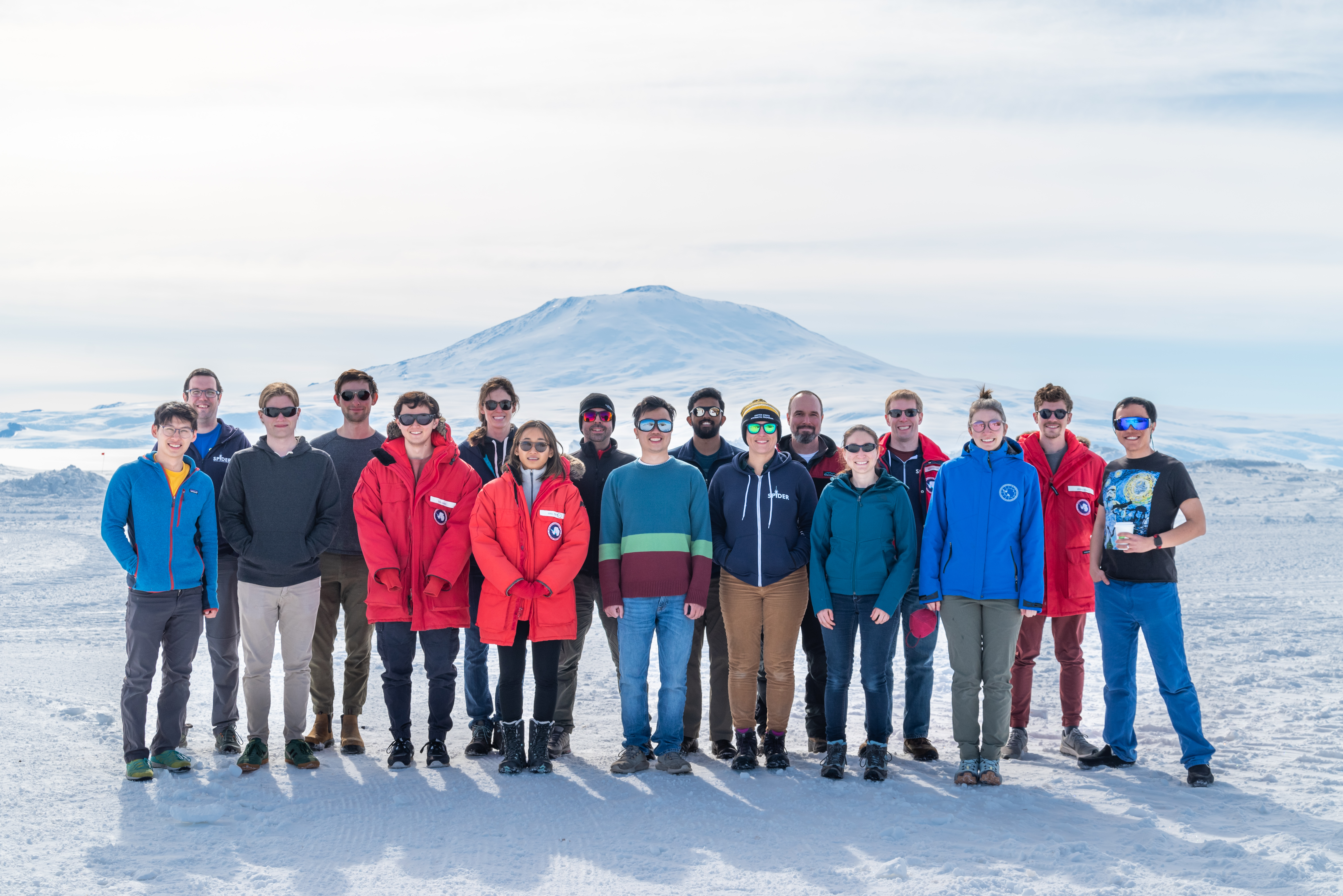 The SPIDER deployment team poses for a photo at the Long Duration Balloon Facility, Antarctica, with Mt. Erebus in the background. Pictured left to right are Corwin Shiu (Princeton), Steven Benton (Princeton), Joseph van der List (Princeton), Simon Tartakovsky (Princeton), Sho Gibbs (UIUC), Elle Shaw (UIUC), Vy Luu (Princeton ), Riccardo Gualtieri (Argonne National Lab), Jason Leung (U. Toronto), Suren Gourapura (Princeton), Sasha Rahlin (U. Chicago), Bill Jones (Princeton), Johanna Nagy (WUSTL), Jeff Filippini (UIUC), Susan Redmond (Princeton ), Jared May (WUSTL), and Steven Li (Princeton ). Photo by Jared May