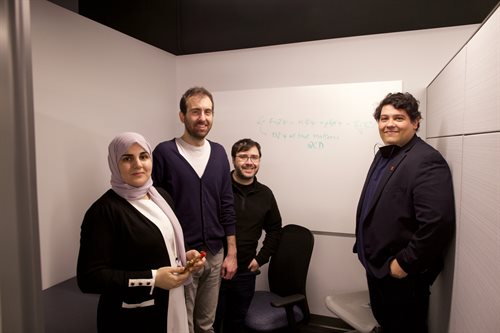 Postdoctoral researchers Dekrayat Almaalol, Enrico Speranza, and Willian Serenone and professor Jorge Noronha pose in front of a white board with an equation and the words &amp;amp;amp;amp;amp;amp;amp;amp;amp;quot;98% of all that matters QCD&amp;amp;amp;amp;amp;amp;amp;amp;amp;quot; written on it.