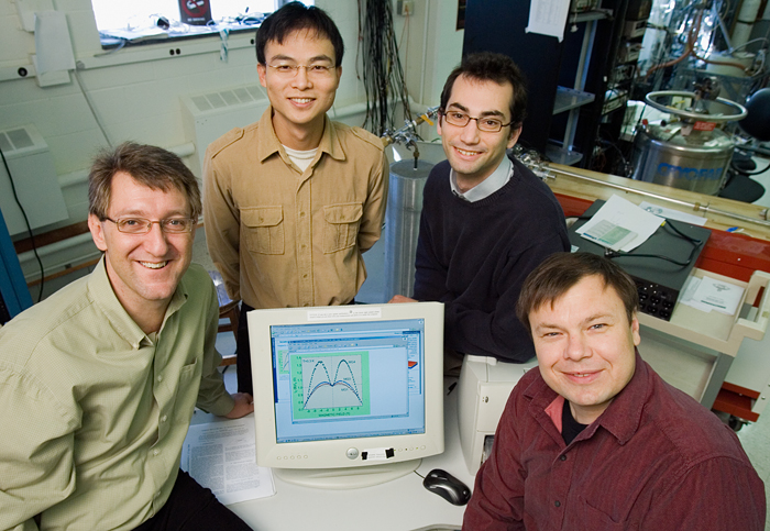 A photo of two professors and two graduate students around a computer in a lab.