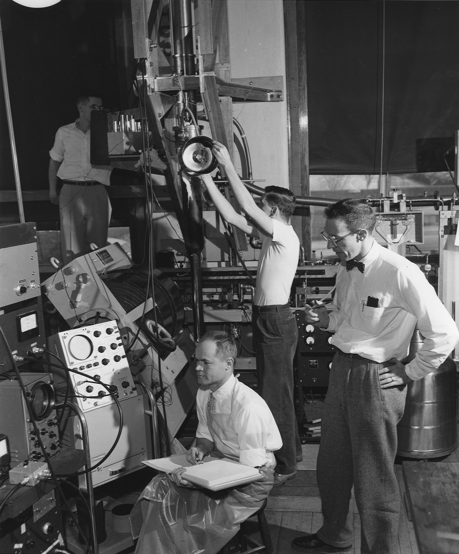 A black and white photograph of men working in a lab in the 50s.